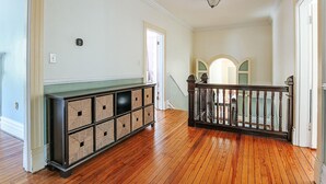 Un couloir doté d’un plancher en bois, d’un meuble de rangement intégré, d’un escalier avec une rampe et d’un luminaire au plafond.