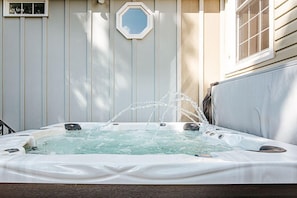 A hot tub with water jets, surrounded by a wooden deck and a house with a window and a door. - Clonmel Acres: Historic Estate with Hot Tub & Pond (Afton)