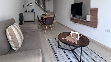 A modern living room with a sofa, a coffee table, and a TV mounted on the wall.