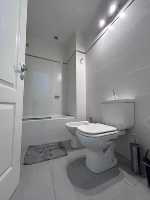 A modern bathroom with a toilet, bidet, and bathtub. - Agustín 1 Apart (Parana)