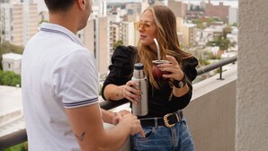 Un hombre y una mujer de pie en un balcón con vistas a la ciudad.