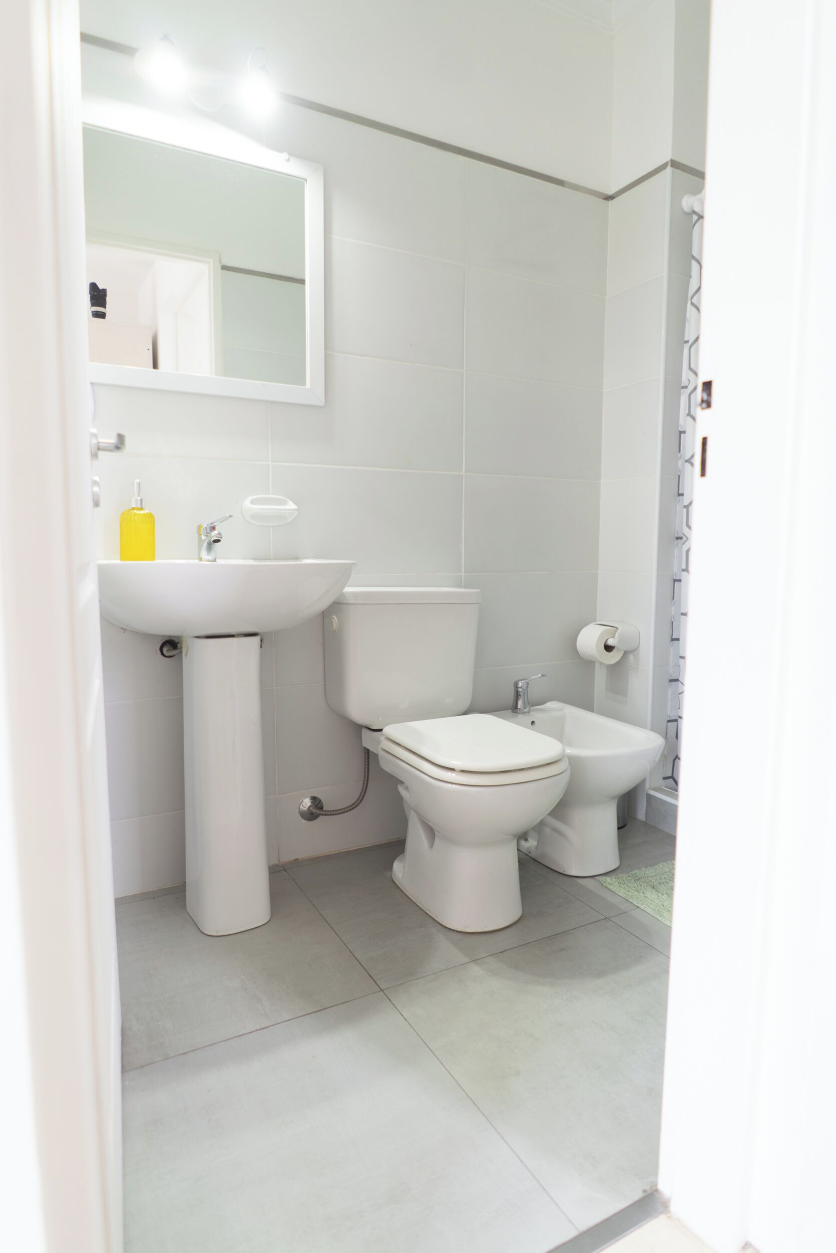 Een moderne badkamer met toilet, hygiëneslot en wastafel.
