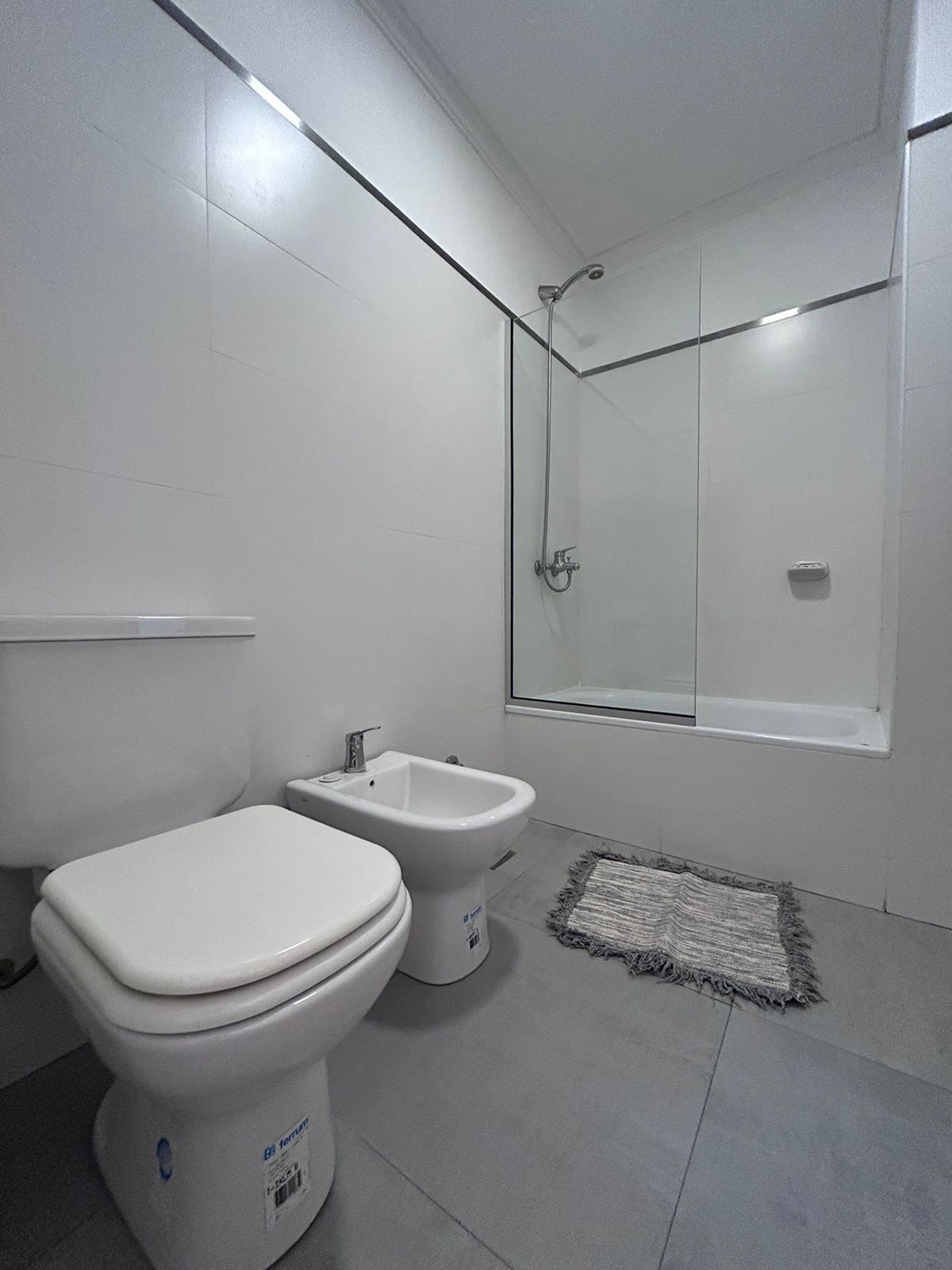 A modern bathroom with a toilet, bidet, and glass-enclosed shower.