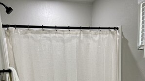 A bathroom with a shower curtain, a toilet, and a towel rack. - Relaxing Hillside Getaway with a Mountain View (Franklin)
