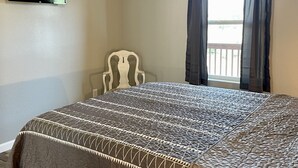 A bedroom with a bed, a ceiling fan, a TV mounted on the wall, and a window with curtains. - Relaxing Hillside Getaway with a Mountain View (Franklin)