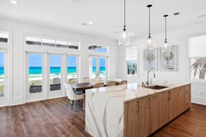 Una cocina con una isla grande, armarios de madera y vista al océano.