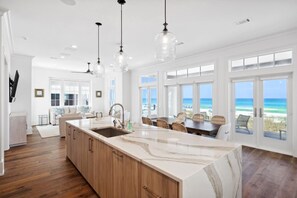 Una cocina amplia con una isla grande, armarios de madera e iluminación colgante.