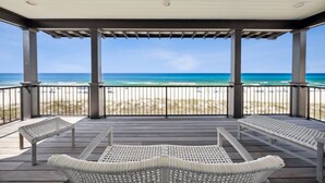 A covered outdoor deck with a view of the beach and ocean.