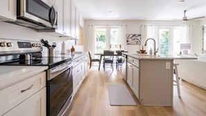 A modern kitchen with white cabinetry, a built-in microwave, and a central island with a sink.