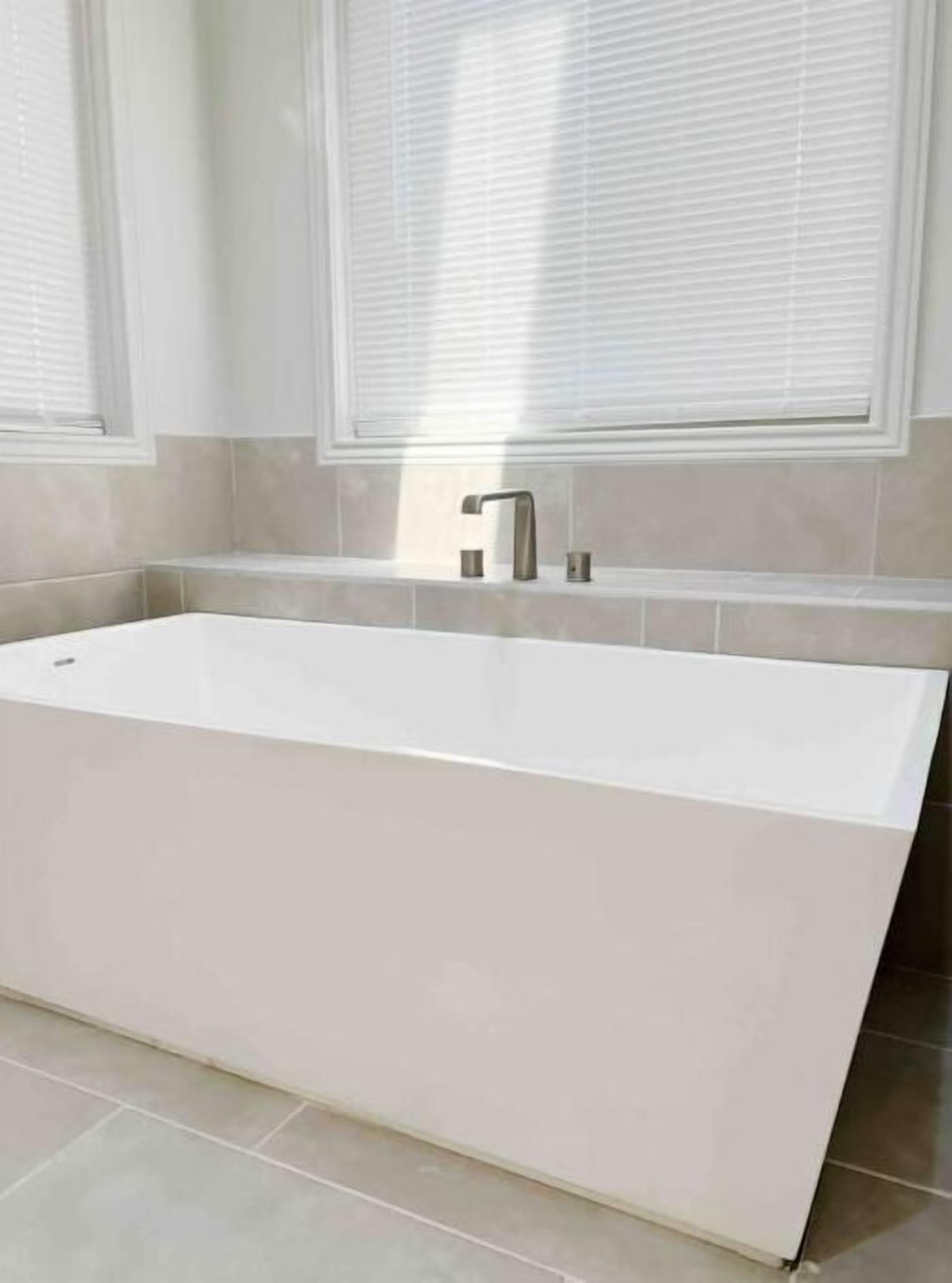 Ein modernes Badezimmer mit einer rechteckigen Badewanne, einem einzelnen Wasserhahn und einem Fenster über dem Waschbecken.