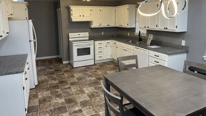 Eine moderne Küche mit weißen Schränken, einer Granitarbeitsplatte, einem Einbauofen und einem Essbereich mit Tisch und Stühlen.