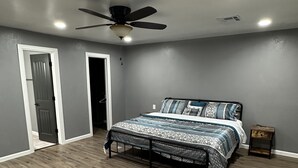 Ein Schlafzimmer mit Bett, Deckenventilator und Nachttisch.
