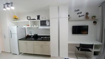 Una cucina compatta con frigorifero, microonde, fornello e un piccolo angolo ristoro.