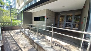 Een modern gebouwtraktement met een metalen hekwerk, een betonnen muur en een deur met glaspanelen.