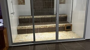 En glasindrammet balkon med fliset gulv og trapper ned til et lille lukket område.