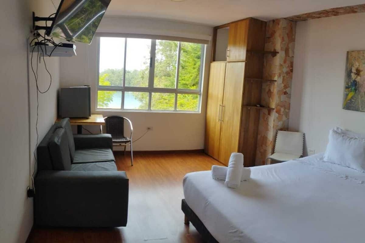 A hotel room with a bed, a desk, a chair, and a wardrobe.