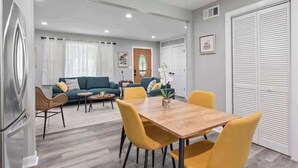 A modern living room with a sofa, coffee table, and dining table. - Relaxing Lake Zurich 3BR + Patio | LCP Collection (Lake Zurich)