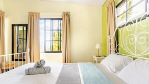 A hotel room with a bed, curtains, a window with a view, a nightstand, and a chair.