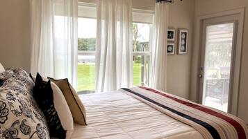 Une chambre à coucher avec un lit, des rideaux blancs et une vue sur un jardin.
