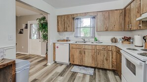 A modern kitchen with wooden cabinets, a dishwasher, a sink, and a stove.