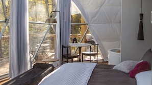 A tented accommodation with a bed, a table, and chairs.