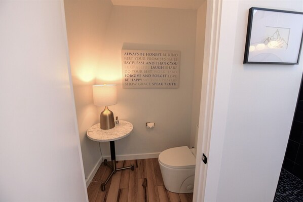 A small bathroom with a marble sink, a standing lamp, and a framed inspirational quote on the wall.