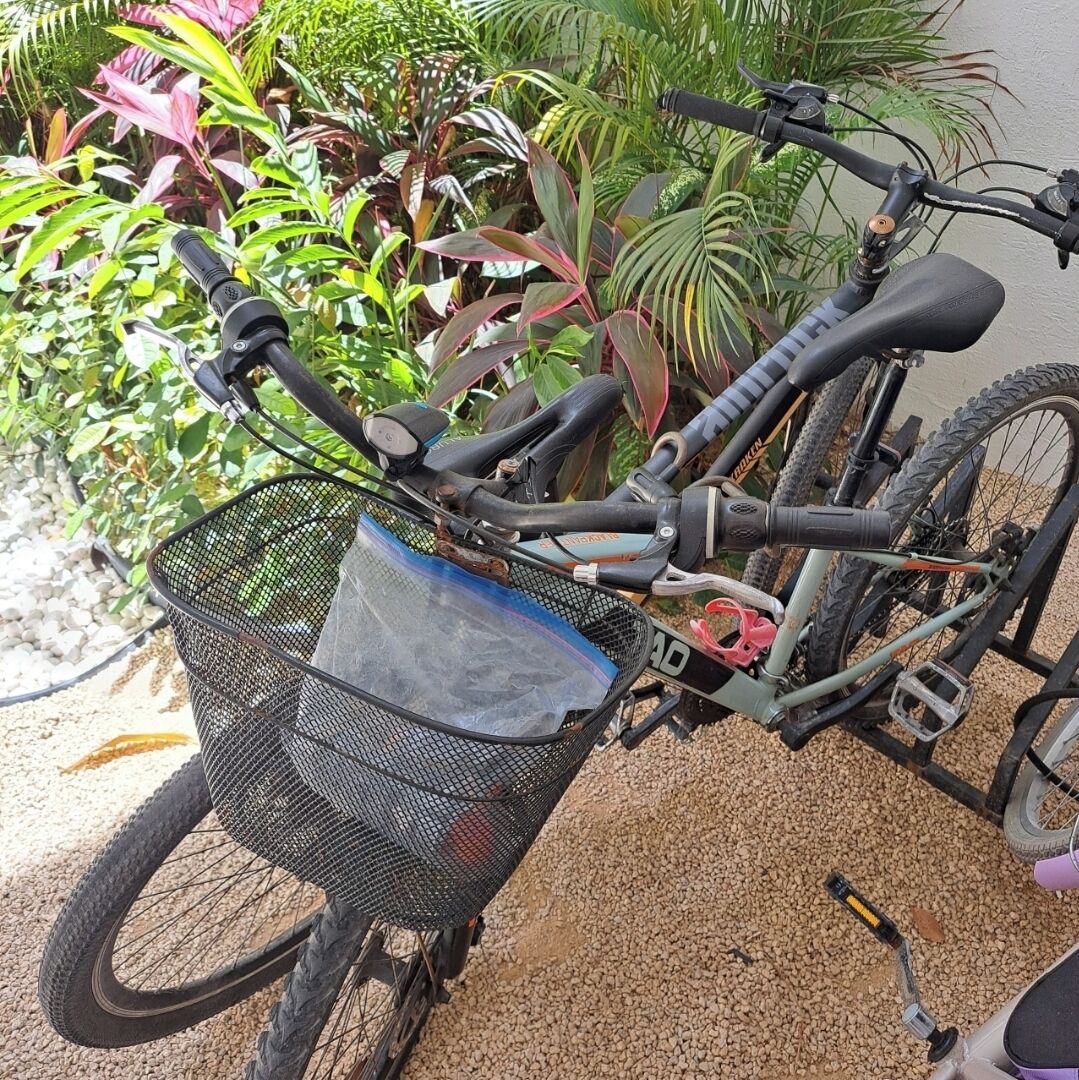 Un vélo avec un panier fixé à l’avant, garé sur une surface de gravier.