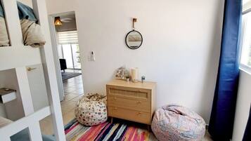 Een kamer met een gestreept tapijt, een houten dressoir, een ronde spiegel en twee zitzakken.