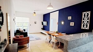 A modern kitchen with a granite countertop, white cabinetry, and a dining area with a wooden table and chairs.