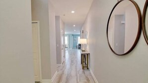 A hallway with a light-colored floor and walls, a round mirror on the right, and a door on the left. - Beautiful Home In Davenport, FL (Davenport)