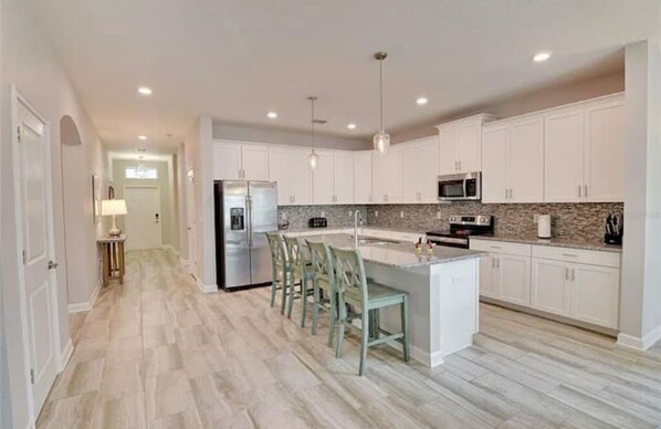 A modern kitchen with white cabinets, a granite countertop, and a central island with bar stools.
