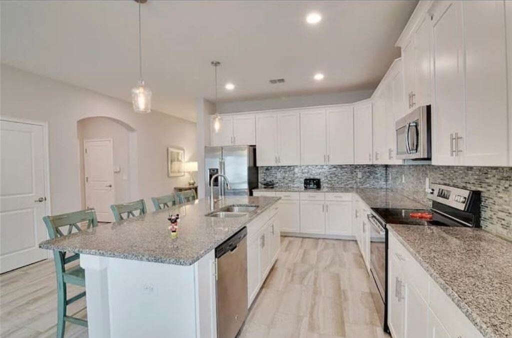A modern kitchen with white cabinets, granite countertops, and a central island.