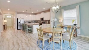 A modern kitchen with white cabinets, a central island, and a dining area with a round table and chairs. - Beautiful Home In Davenport, FL (Davenport)