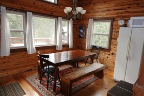 A wooden cabin with a dining table, chairs, a bench, and a refrigerator. - SplitRock Cabin, Ponderosa California. A Log Cabin Paradise! (Springville)
