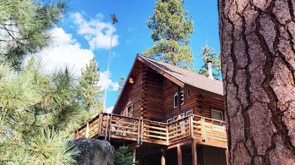 A log cabin with a wooden deck and a stone wall. - SplitRock Cabin, Ponderosa California. A Log Cabin Paradise! (Springville)