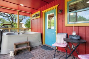 A hot tub, a door, a chair, and a table with a radio. - Stronghold Red Cloud | Creekside Cabin w/ Hot Tub (Bandera)