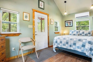 A bedroom with a bed, dresser, chair, and a door. - Stronghold Red Cloud | Creekside Cabin w/ Hot Tub (Bandera)