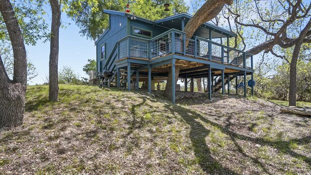 A two-story house with a balcony, surrounded by trees. - Bandera Stronghold Crazy Horse (Bandera)