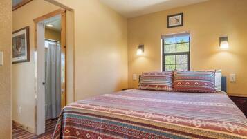 A bedroom with a bed, a window, and a door leading to another room.