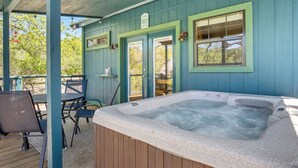 Ein Whirlpool unter einer überdachten Terrasse mit Tisch und Stühlen, ein Holzdeck und eine Tür mit einem Schild.