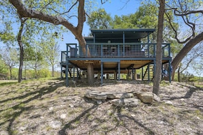 A treehouse with a wooden deck, a balcony, and a metal railing.