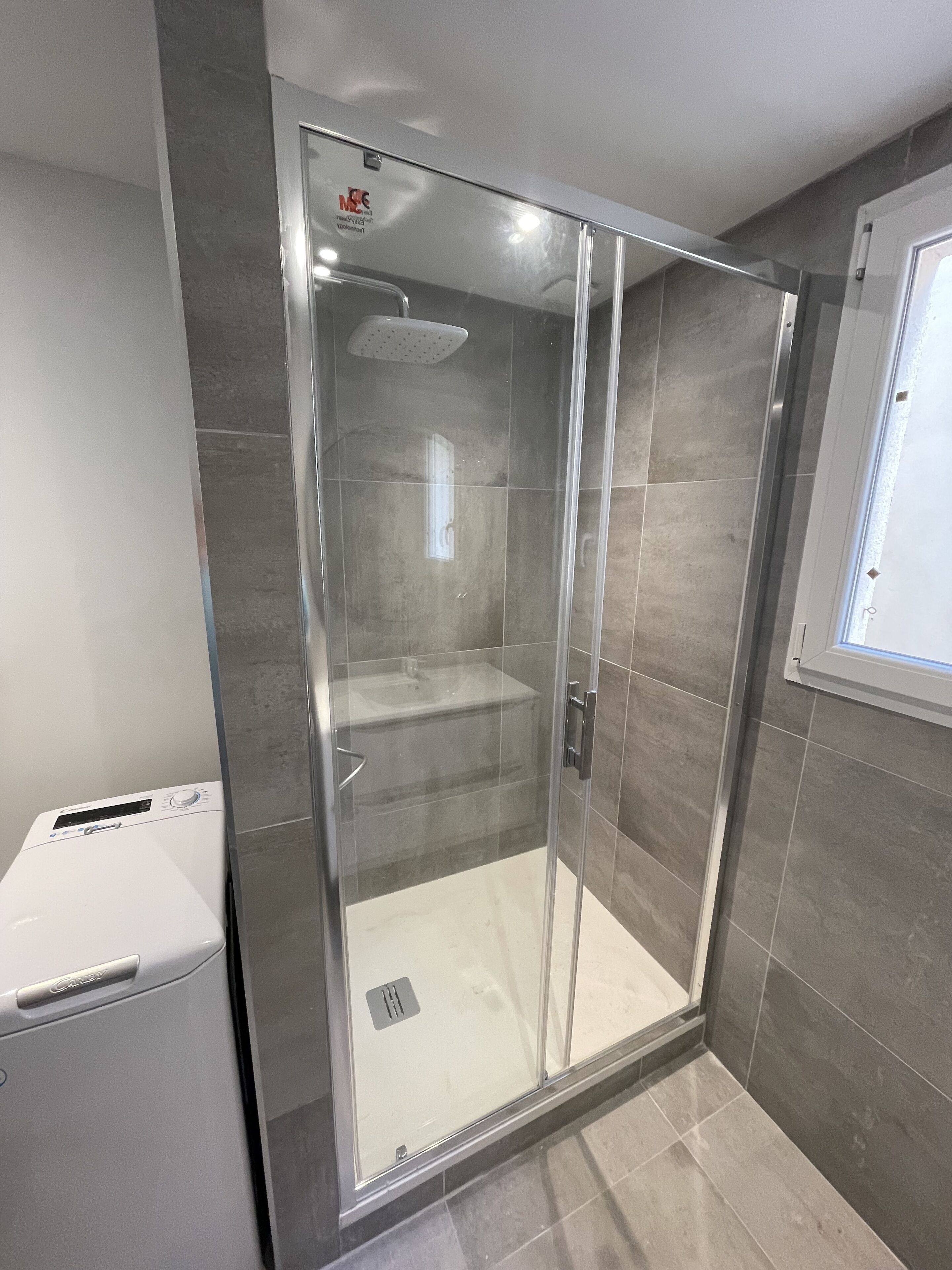 Ein modernes Badezimmer mit einer gläsernen Duschkabine, einem integrierten Waschbecken und einer Toilette.