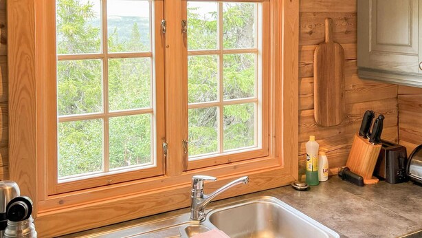 Una cocina con un amplio ventanal, armarios de madera y un lavamanos de acero inoxidable.