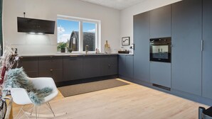 Una cucina moderna con mobili scuri, forno integrato e una finestra che offre vista sull'esterno.