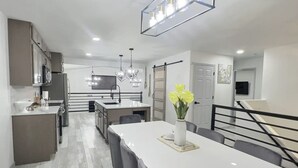 A modern kitchen with a central island, stainless steel appliances, and a dining area with a white table and chairs. - Loveland Oasis w/ Indoor Heated Pool & Game Room (Loveland)