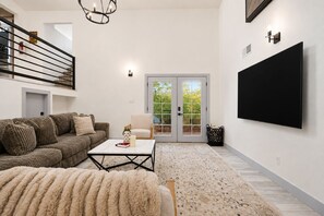 A modern living room with a sectional sofa, a coffee table, a fluffy rug, a television, and a sliding glass door leading to a balcony. - Loveland Oasis w/ Indoor Heated Pool & Game Room (Loveland)