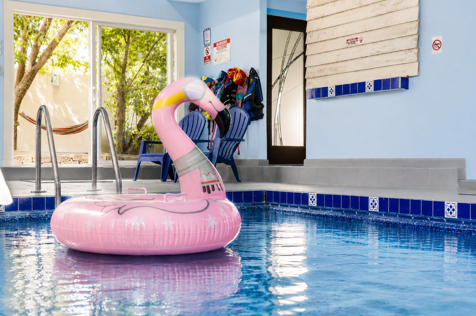 A swimming pool with a pink inflatable flamingo float, a hammock, and a chair.