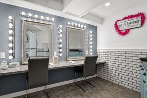 Un baño con dos espejos, iluminación, un tocador y un cartel que dice 'in our home LOVE & LAUNDRY'.