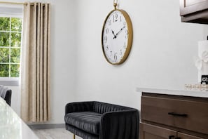 A modern kitchen with a wall-mounted clock, a dining table, and a black upholstered chair. - Loveland Oasis w/ Indoor Heated Pool & Game Room (Loveland)