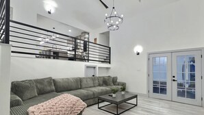 A modern living room with a sectional sofa, a coffee table, and a staircase leading to an upper level. - Loveland Oasis w/ Indoor Heated Pool & Game Room (Loveland)
